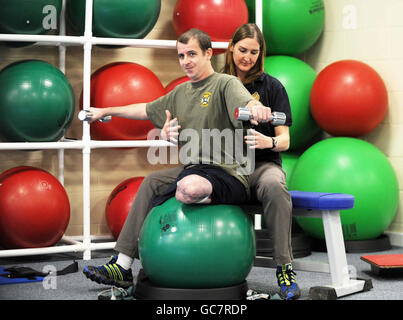 Sergeant Gavin Harvey, 26, der während der Operation Panther's Claw in Afghanistan im August beide Beine verloren hatte, arbeitet mit dem Physiotherapeuten Sindy Rollins im Tidworth Garrison Super-Gym and Regional Rehabilitation Center im Tidworth Camp in Wiltshire an einigen Übungen. Stockfoto