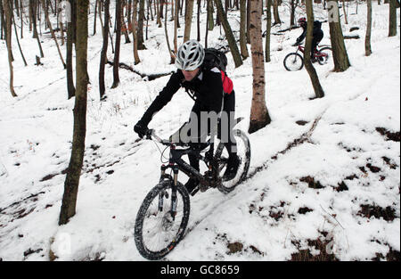 Mountainbiker schaffen es in Innerleithen in den Scottish Borders bergauf durch starken Schnee. Stockfoto