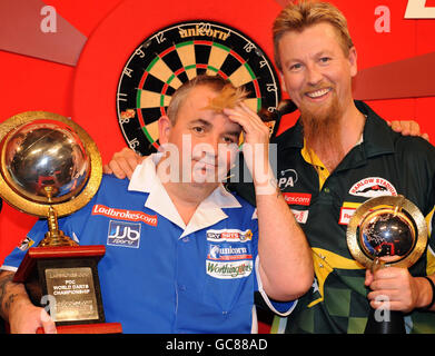 Phil Taylor (links) feiert seinen Sieg über Simon Whitlock im Finale während der World Darts Championship Ladbrokes.com im Alexandra Palace, London. Stockfoto