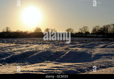 Die Sonne beginnt über einem schneebedeckten Feld in Barkby, Leicestershire untergehen. Stockfoto