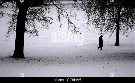 Ein Mann geht durch den Schnee im Christchurch Park im Zentrum von Ipswich, Suffolk. Stockfoto