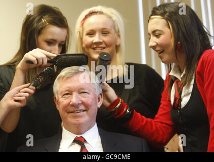 Manchester United Manager Sir Alex Ferguson mit Studenten (von links nach rechts) Nicola Hunter, Emma Hanley und Mairead Linning, bei einem Besuch in der Friseurabteilung seiner ehemaligen Schule, der Govan High School, die in diesem Jahr ihr 100-jähriges Bestehen feiert. Stockfoto