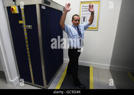 Ein BAA-Sicherheitsbeauftragter (Name nicht angegeben) demonstriert die neuen Körperscanner am Flughafen Heathrow in Middlesex. Verkehrssekretär Lord Adunisist versuchte heute, die Befürchtungen hinsichtlich der Privatsphäre hinsichtlich der Einführung von Ganzkörperscans auf Flughäfen zu zerstreuen. Stockfoto