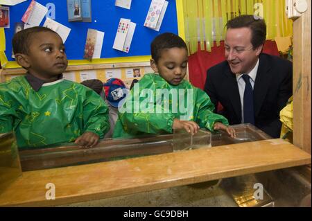 Tory-Führer David Cameron wird mit den 3-jährigen Zwillingen Mubeen und Wuneeb Tingari während eines Besuchs in einer Londoner Kindertagesstätte der Early Years Foundation in London abgebildet. Stockfoto