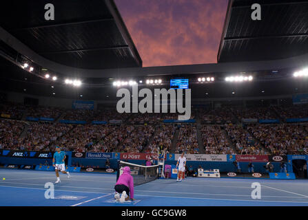 Der britische Andy Murray (rechts) spielt einen Fallschuss gegen den Schweizer Roger Federer, als die Sonne über der Rod Laver Arena während des Finales der Australian Open im Melbourne Park, Melbourne, untergeht. Stockfoto