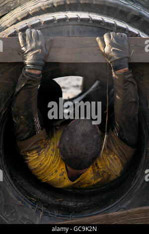 Ein Teilnehmer während des Reifensturls von Tough Guy Stockfoto