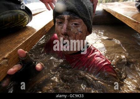 Ein Wettbewerber während tritt während des aus dem Wassertunnel aus „Tough Guy“-Herausforderung Stockfoto