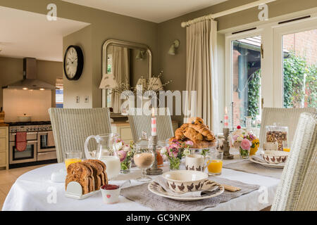 Tisch gedeckt mit Frühstück Croissant und Toast. Die Esszimmerstühle sind Fulham Lloyd und Webstuhl. Stockfoto