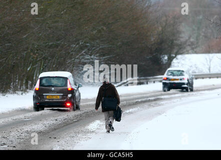 Ein Mann geht nach einer Nacht mit starkem Schneefall zur Arbeit entlang der A28 in Ashford, Kent. Stockfoto