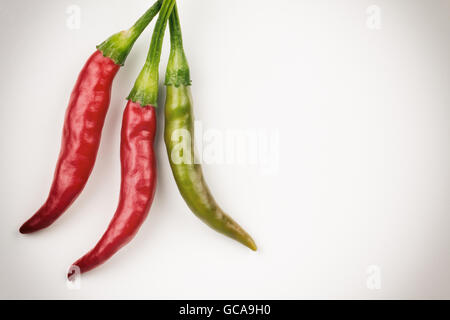 Zwei rote und eine grüne Thai Chili Peppers, verarbeitet mit Filter und Vignette. Foto mit textfreiraum hautnah. Stockfoto