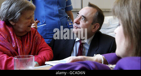 Der schottische Premierminister Alex Salmond und die Gesundheitsministerin Nicola Sturgeon (rechts) unterhalten sich mit der Patientin Florence Gilmour (links) während eines Besuchs zur offiziellen Eröffnung des New Victoria Hospital in Glasgow. Stockfoto