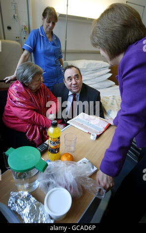 Der schottische Premierminister Alex Salmond und die Gesundheitsministerin Nicola Sturgeon (rechts) unterhalten sich mit der Patientin Florence Gilmour (links) während eines Besuchs zur offiziellen Eröffnung des New Victoria Hospital in Glasgow. Stockfoto