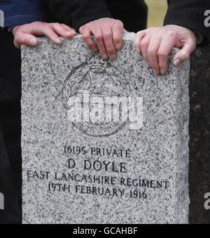 Verwandte Hände auf dem Grabstein von Dennis Doyle auf Cambusnethan Friedhof, North Lanarkshire, 94 Jahre zu dem Tag, an dem er im Ersten Weltkrieg getötet wurde. Die Commonwealth war Graves Commission hat kürzlich einen Grabstein für den Soldaten errichtet, der im East Lancashire Regiment diente, nachdem seine letzte Ruhestätte entdeckt wurde. Stockfoto