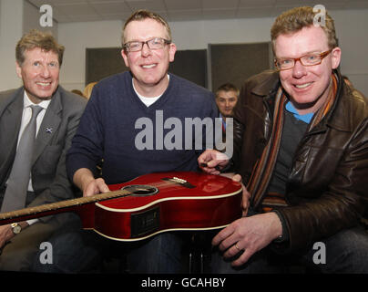 Justizsekretär Kenny MacAskill (links) schließt sich Charlie Reid (Mitte) und Craig Reid (rechts) von den Verkündern bei einem Besuch bei Reeltime Music in Newarthill, Schottland, an. Stockfoto