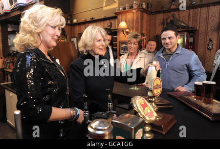 Die Herzogin von Cornwall zieht ein Pint Bier, während sie die Schauspieler Beverley Callard trifft, die Wirtin Liz McDonald (links), Anne Kirkbride, die die Rolle von Deirdre Barlow und Ryan Thomas spielt, Die die Rolle von Jason Grimshaw bei einem Besuch der Rovers Return während ihres Besuchs an der Set of Coronation Street in Manchester spielt. Stockfoto