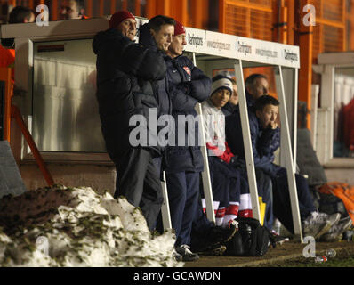 (L-R) Arsenals Youth Team Manager Steve Bould, der Academy-Torwarttrainer Tony Roberts und der Academy-Trainer Steve Gatting sehen das Spiel von der Seitenlinie aus, neben einem Haufen Schnee, während ihrer vierten Runde des FA Youth Cup gegen Ipswich Town im Underhill Stadium in Barnett. Stockfoto