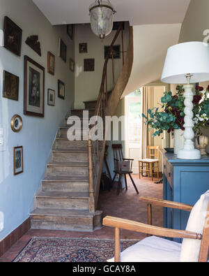 Eingangshalle mit Terracottafliesen, Holztreppe und Orientteppich Stockfoto