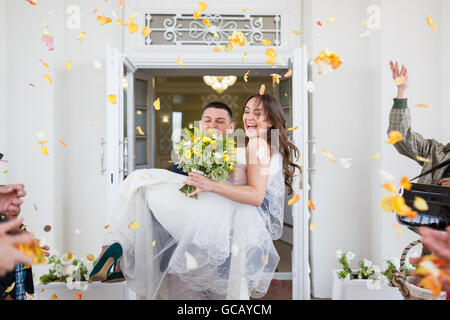 Glückliches Hochzeitspaar unter der Dusche von Blütenblättern Stockfoto