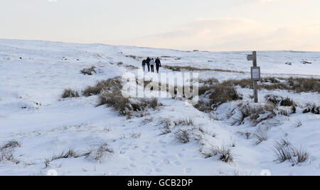 Spaziergänger auf den Hügeln über Reeth in den Yorkshire Dales, als heute in vielen Teilen Großbritanniens wieder Schnee kam. Stockfoto