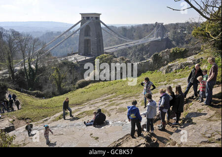 Kinder und Erwachsene nutzen das sonnige Wetter in Bristol voll und ganz und rutschen bei kaltem, aber sonnigem Wetter über die Felsen in der Nähe der Clifton Suspension Bridge in Bristol. Stockfoto