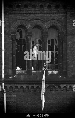 Der Häftlingsführer Paul Taylor tritt im Morgengrauen gegen die zerstörten Rotunda-Fenster des Strangeways-Gefängnisses in Manchester auf, nachdem sechs Insassen, die noch immer verbarrikadiert waren, Feuer ausgelöst hatten. Stockfoto