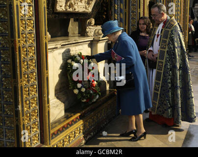 Die britische Königin Elizabeth II., die von Reverend John Hall (rechts), dem Dekan der Westminster Abbey, beobachtet wird, legt während des jährlichen Commonwealth Day Observing Service einen Kranz auf das Grab von Sir Isaac Newton in der Westminster Abbey. Stockfoto