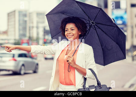 glücklich afrikanische Frau mit Regenschirm Fang taxi Stockfoto