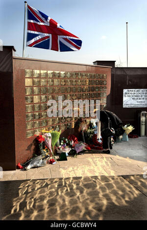 Eine Frau legt an der Basra Memorial Wall im National Memorial Arboretum in der Nähe von Alrewas in Staffordshire Blumen an gefallene Servicemitarbeiter, nachdem sie aus Basra, Irak, verlegt wurde. Stockfoto