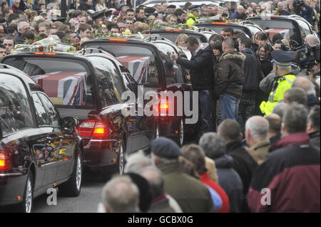 Trauernde versammeln sich um die Leichenwagen und ein Mann lehnt sich auf den Leichnam, der den Leichnam von Rifleman Jonathon Allott enthält, während die Särge von Liam Maughan, Lance Corporal Thomas Keogh, Corporal Stephen Thompson, Rifleman Jonathon Allott und Corporal Richard Green durch die High Street von Wootton Bassett fahren, Wiltshire nach der Repatriierungszeremonie bei RAF Lyneham. Stockfoto