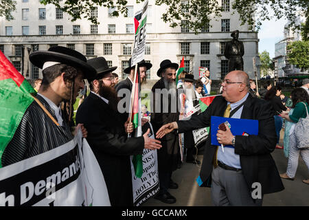 London, UK. 8. Juli 2016. Kamal Hawwash von Palestine Solidarity Campaign schüttelt Hände mit einer Gruppe von orthodoxen Juden bei pro-palästinensische "Ende der Belagerung auf Gaza" Rallye gegenüberliegenden Downing Street. Wiktor Szymanowicz/Alamy Live-Nachrichten Stockfoto