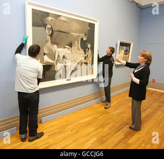 Fionnuala Croke, Leiterin der Sammlungen der National Gallery of Ireland in Dublin, beobachtet, wie Kunsthändler Louis Le Brocquys 'A Family' bei den letzten Vorbereitungen für die Installation der Ausstellung Taking Stock: Acquisitions 2000-2010 aufhängen. Stockfoto