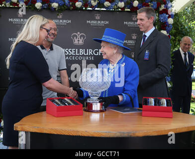 Königin Elizabeth II präsentiert Musselburgh Bi-Hundertjahrfeier Cup an die Besitzer von Livella Fella im Gewinner-Gehäuse, beobachtet von der Duke of Edinburgh (hinten rechts), während eines Besuchs in Musselburgh Pferderennbahn in East Lothian, Schottland. Stockfoto