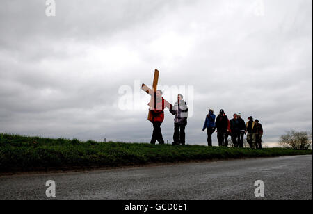 Pilger vom Studentenkreuz tragen in Cambridgeshire ein großes Holzkreuz entlang einer zehn Kilometer langen Talsohle, während sie zur Slipper-Kapelle am römisch-katholischen Schrein in Walsingham Norfolk wandern. Stockfoto