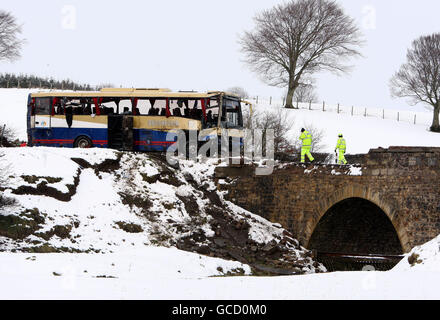 Die Polizei schaut auf den abgestürzten Schulbus, nachdem er von der Absturzstelle an einer Brücke auf der A73 in der Nähe von Wiston in Schottland geborgen wurde. Stockfoto