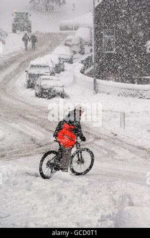 Ein Radfahrer im schweren Schnee, der Straßen in Peebles in den schottischen Grenzen und in ganz Schottland bedeckt. Stockfoto