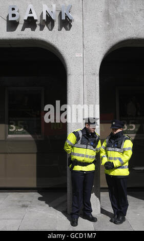 Mitglieder der Gardai im Dienst als Mitglieder der Socialist Party protestieren vor einer Zweigstelle in St. Stephen's Square, Dublin der Anglo-Irish Bank, nachdem die unruhige Institution die größten Unternehmensverluste in der irischen Geschichte angekündigt - 12.7 Milliarden Euro (11.3 Milliarden). Stockfoto