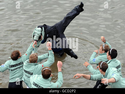 Cambridge cox Ted Randolph wird von Teamkollegen ins Wasser geworfen, als sie den Sieg beim 156. Bootsrennen auf der Themse in London feiern. Stockfoto