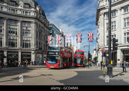 London Red Bus reisen entlang der Oxford Street im Freien an einem sonnigen Tag in Stadt Pendler und Verkehr mit Union Jack-Flaggen Stockfoto