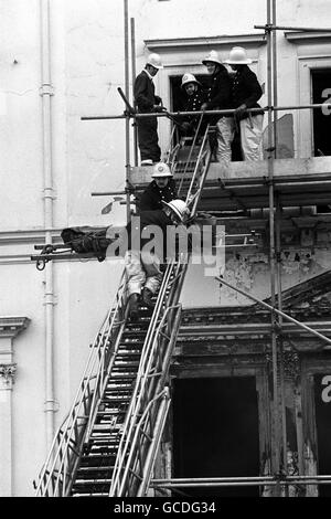 Feuerwehrleute, die eine von zwei Leichen entfernen, die bisher in den verbrannten Resten der iranischen Botschaft in London gefunden wurden. Die Leiche, in einen dunkelgrünen Leichensack gewickelt, wurde von einem Fenster im zweiten Stock des Gebäudes im Princes Gate, Kensington, abgesenkt und von einem Leichenwagen mitgenommen. Stockfoto