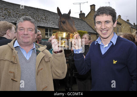 Nigel Twiston-Davies, Trainer des Cheltenham Gold Cup 2010 Gewinners, hält den Pokal mit Jockey Paddy Brennan (rechts) während der Siegesparade vor dem Hollow Bottom Pub in Guiting Power, in der Nähe von Cheltenham. Stockfoto