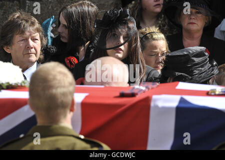 Charlotte Fox (Mitte), Witwe von Sergeant Paul Fox von 28 Engineer Regiment, der Brigade Reconnaissance Force angeschlossen, steht mit Paul's Vater Maurice Fox (links) hinter der Flagge drapiert Sarg bei seinem Trauerdienst in St. Ia's Church, St. Ives, Cornwall. Stockfoto