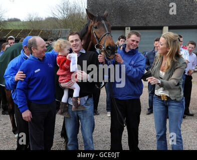 Jockey Tony McCoy hält seine Tochter Eve im Alter von 2, neben Don't Push IT, die von Bräutigam Alan Berry mit Trainer Jonjo O'Neill (links) und Tonys Frau Chanelle (rechts) während der Parade im Plough Inn bei Ford, Temple Guiting gehalten wird. Stockfoto