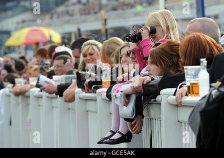 Eine junge Rennfahrerin hat die Aktion am Ladies Day des Grand National Meetings auf der Aintree Racecourse, Liverpool, im Auge. Stockfoto