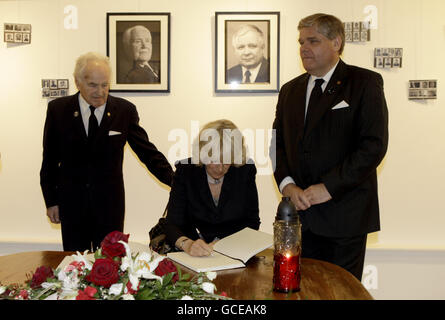 Camilla, die Herzogin von Cornwall (Mitte), unterzeichnet in London das Kondolenzbuch für den polnischen Präsidenten Lech Kaczynski, flankiert vom Vorsitzenden des Zentrums, Dr. Olgierd Lalko (rechts), und dem stellvertretenden Vorsitzenden Artur Rynkiewicz (links). DRÜCKEN SIE VERBANDSFOTO. Bilddatum: Donnerstag, 22. April 2010. Der polnische Präsident, seine Frau und einige der prominentesten Führer des Landes starben am 10. April, als das Präsidentenflugzeug abstürzte, als es auf dem Flughafen Smolensk in Westrussland landete. Camilla ist vorübergehend in einem Rollstuhl, nachdem sie ihr Bein gebrochen hat Stockfoto