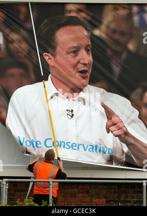 Ein Arbeiter ersetzt eine entstellte Plakatwand der Konservativen Partei durch ein neues Plakat, das den konservativen Parteiführer David Cameron zeigt. Stockfoto