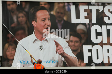 Ein Arbeiter ersetzt eine entstellte Plakatwand der Konservativen Partei durch ein neues Plakat, das den konservativen Parteiführer David Cameron zeigt. Stockfoto