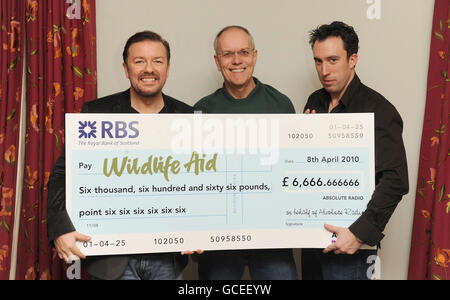 Ricky Gervais und Christian O'Connell präsentieren Simon Cowell von Wildlife Aid mit einem Scheck, nachdem Ricky die meisten Stimmen für den "Who's Calling Christian?" gewonnen hat. Steckplatz auf Absolute Radio. Stockfoto