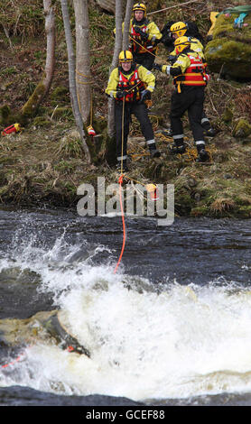 Rettungskräfte ziehen an Seilen, während sie versuchen, ein Kajak, das im Fluss Tay in Grandtully unter Wasser getaucht ist, nach dem Tod des 19-jährigen Mannes, der gestern beim Kajakfahren unter Felsen auf dem Fluss Tay in Schottland gefangen war, wieder zu finden. Stockfoto