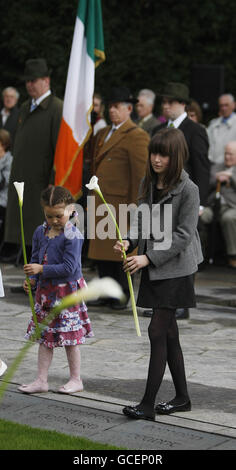 Meadhbh, 9, (rechts), Tochter von Taoiseach Brian Cowen, bereitet sich darauf vor, während der jährlichen Fianna Fail Easter Rising Comemoration in Arbour Hill, Dublin, eine Lilie an den Gräbern der irischen Führer des Aufstands von 1916 zu legen. Stockfoto