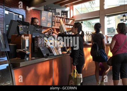Frau mit Apple Pay zu bezahlen ihren Kaffee im Starbucks Coffee shop Stockfoto